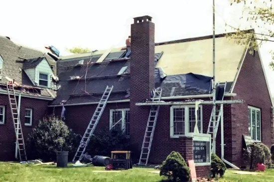 James Stirling and crew re-roofing a brick church building with ladders and scaffolding on an earlier commercial roofing project from 2002.
